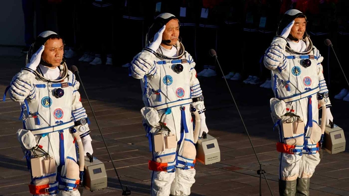 Ba phi hành gia Trung Quốc giơ tay chào trước khi lên tàu Thần Châu để tới trạm vũ trụ Thiên Cung ngày 17/6. Ảnh: AFP.